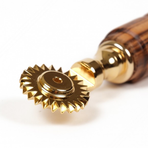 Golden brass pasta cutter with single toothed blade. Maple wood handle